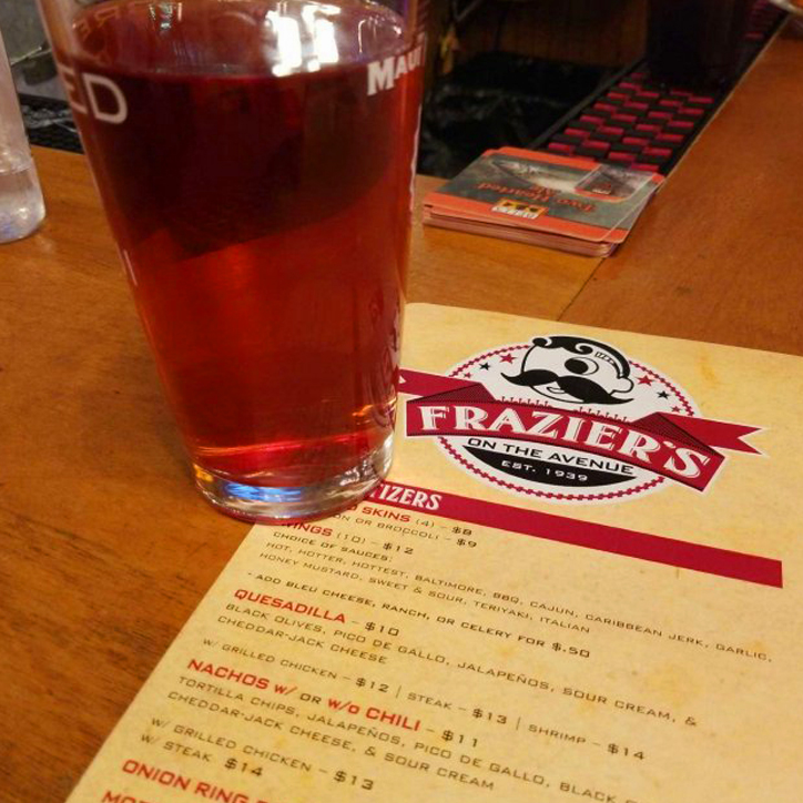 pint glass of beer sitting on a Frazier’s on the Avenue menu pint glass of beer sitting on a Frazier's on the Avenue menu