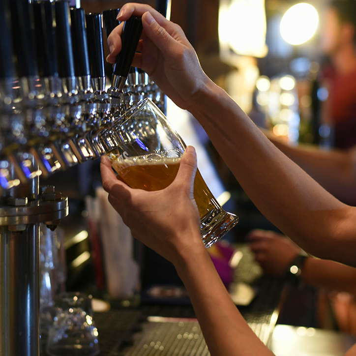 image showing a hand pulling a beer tap to fill a pint glass image showing a hand pulling a beer tap to fill a pint glass