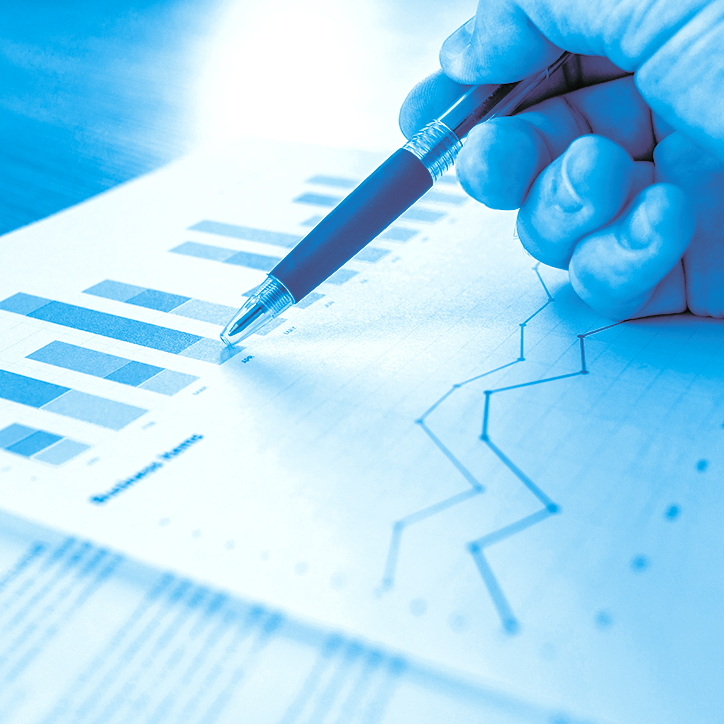 hand holding a pen looking over graphs on paper